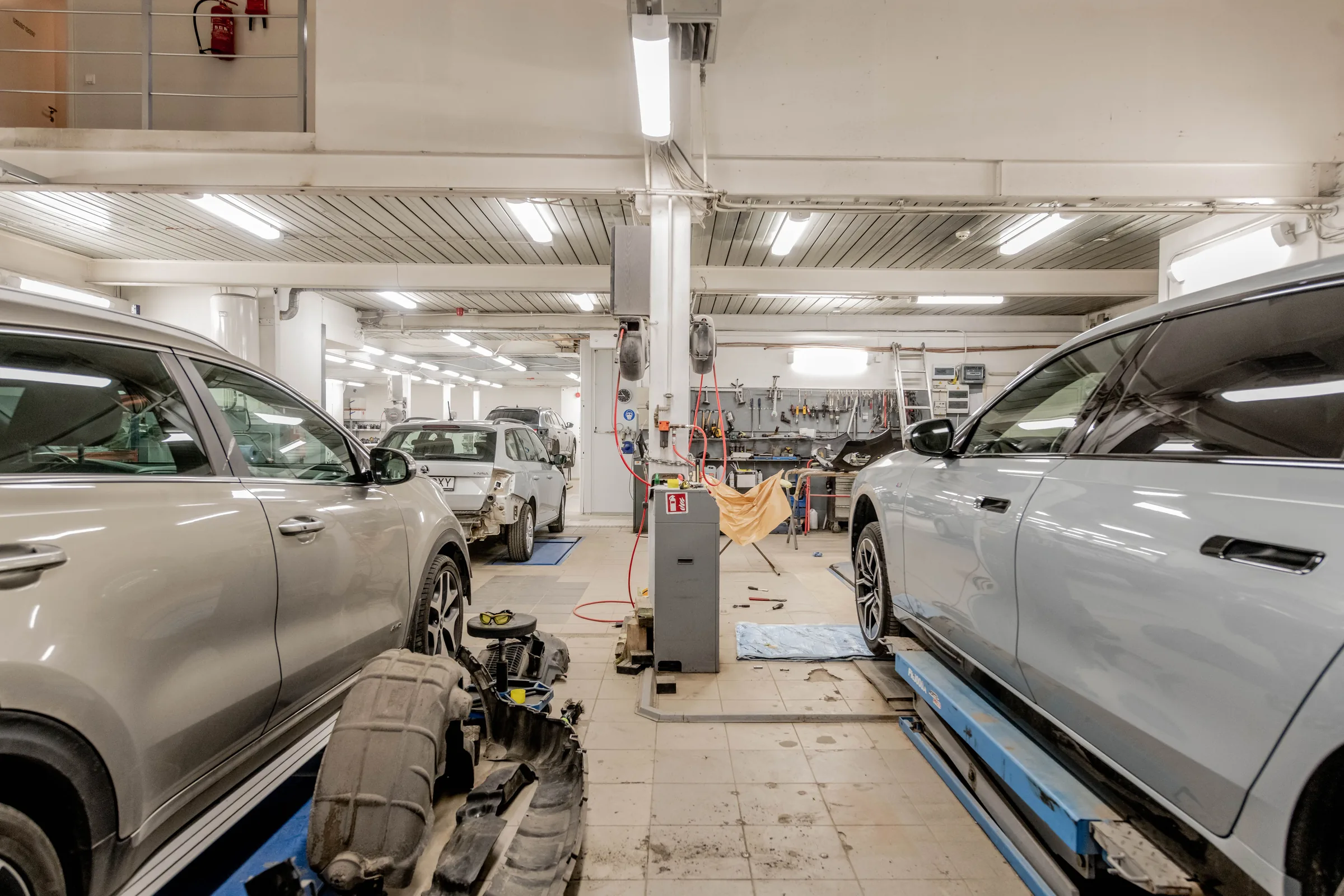 Ilustrační pohled do automobilové dílny s vozy na pracovištích